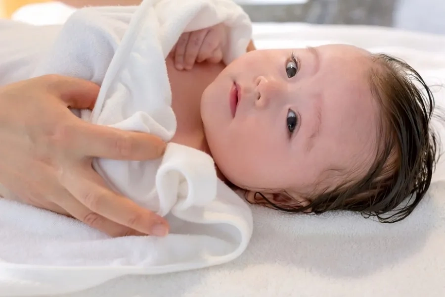 Sau khi tắm dùng khăn sạch thấm khô để không gây tổn thương da của bé